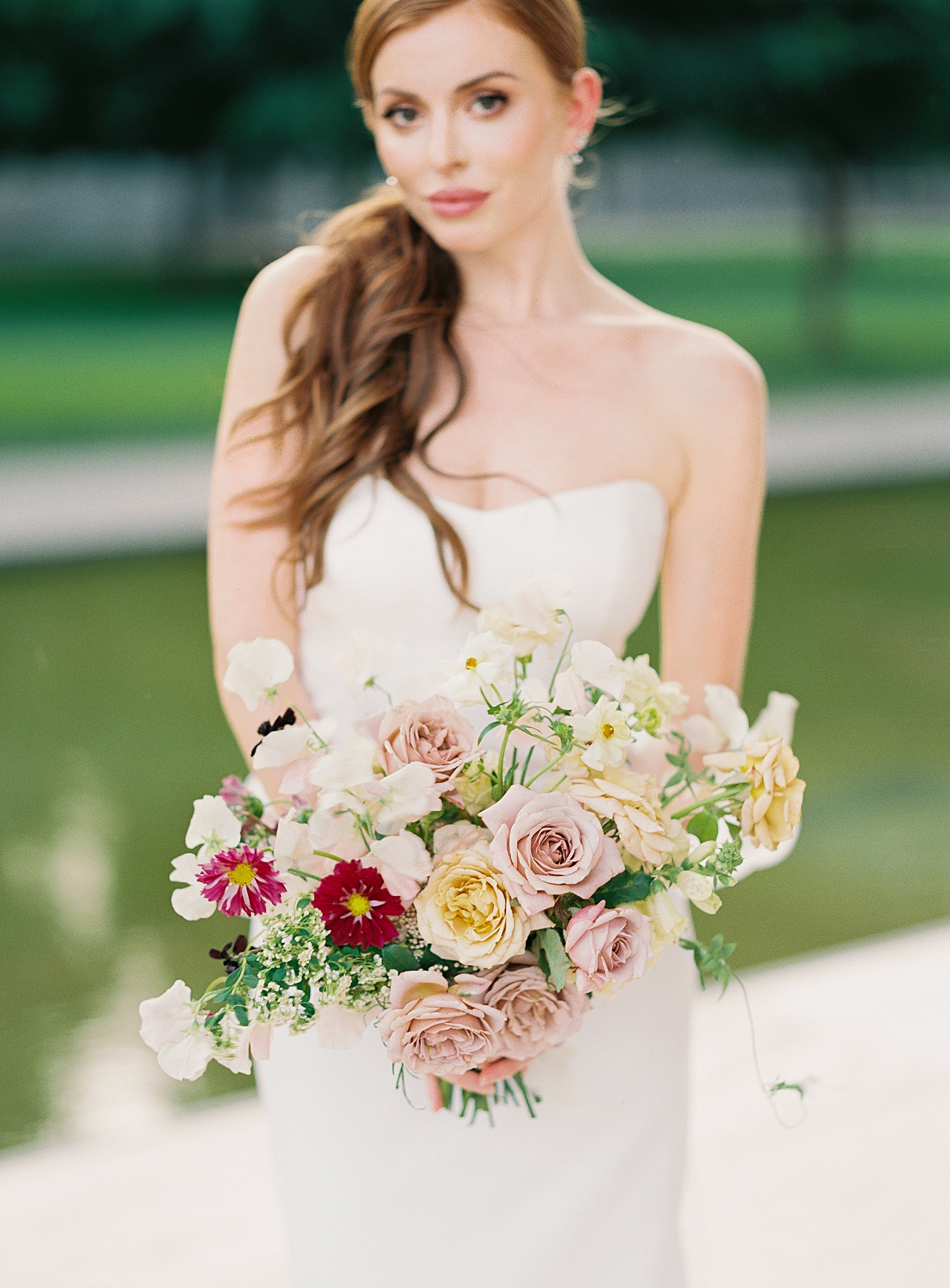 red headed girl in white wedding gown holding colorful bridal bouquet
