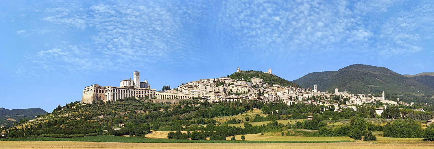 Assisi Perugia, Italy town on green hill in front of mountains blue sky in Tuscany