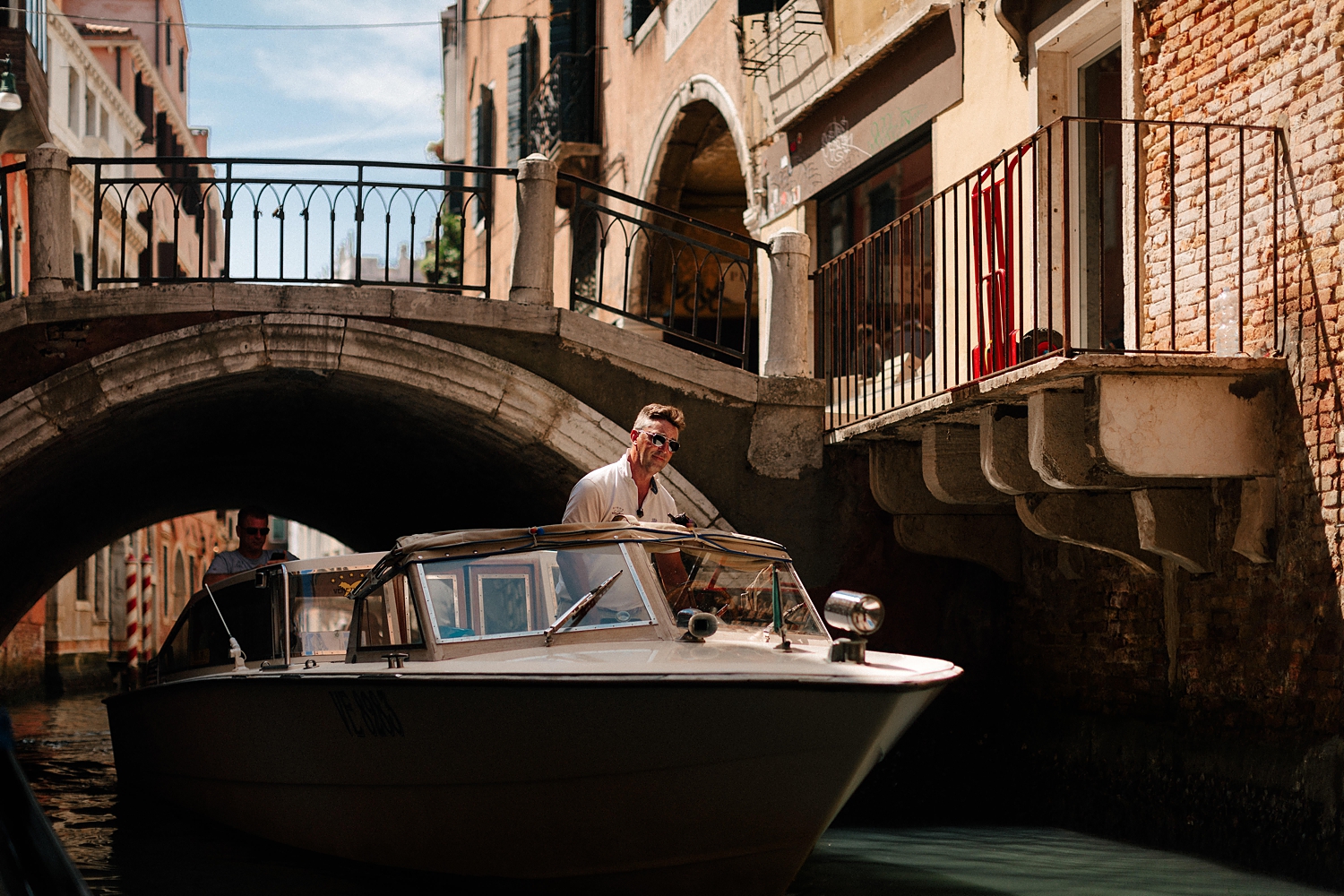 Venice Canal scene with man in boat and passing under small bridge