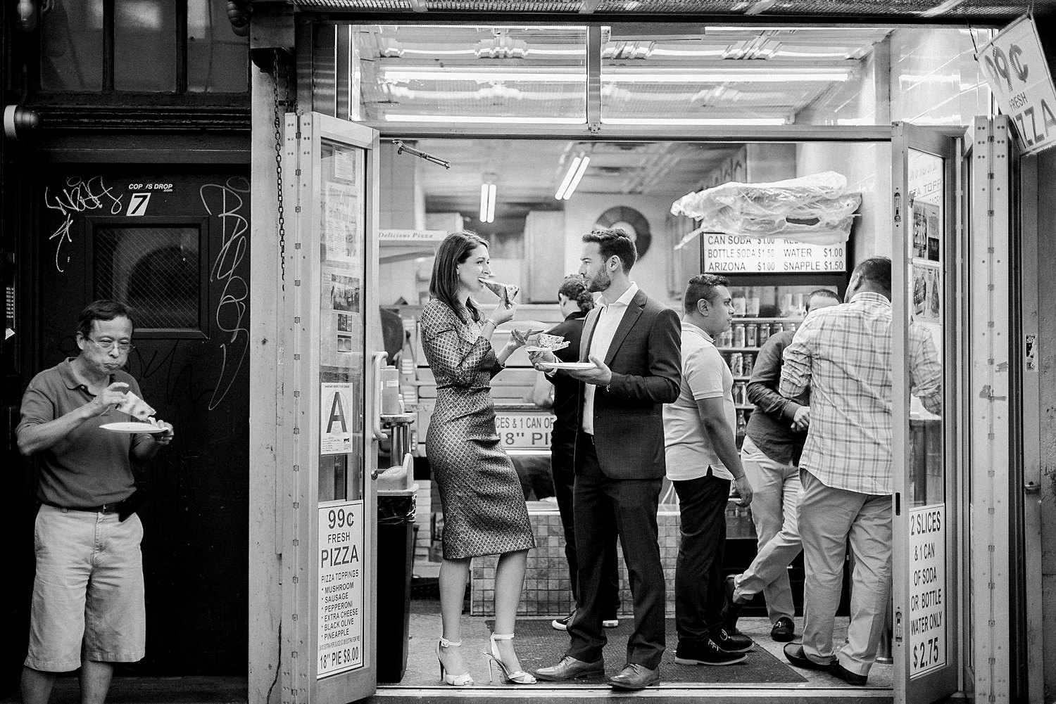 man and woman eating pizza in new york city pizzeria open to sidewalk Black and white