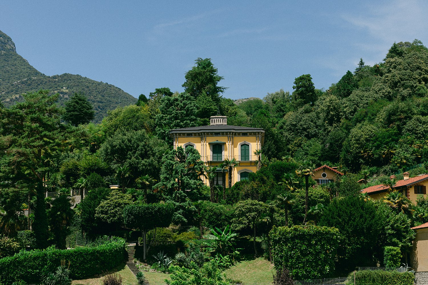 yellow Italian home in green garden overlooking mountains Italy