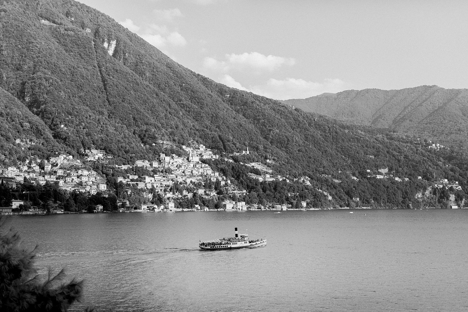 Italian village on the shore of lake Como below mountain Italy black and white steamboat