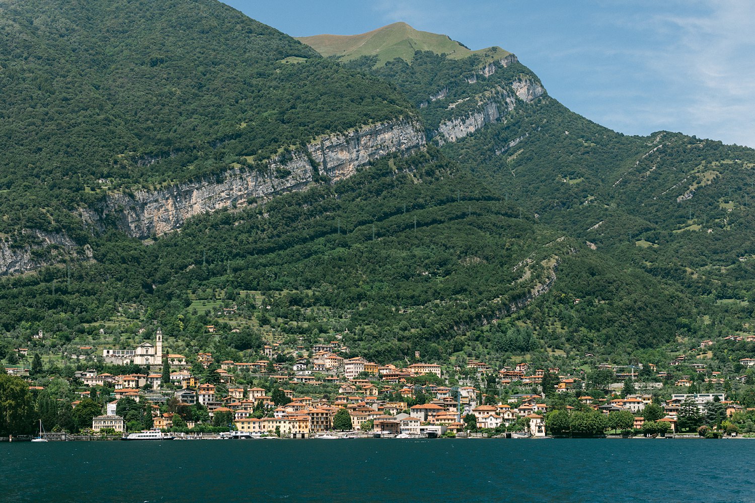 Italian village on the shore of lake Como below green mountain Italy