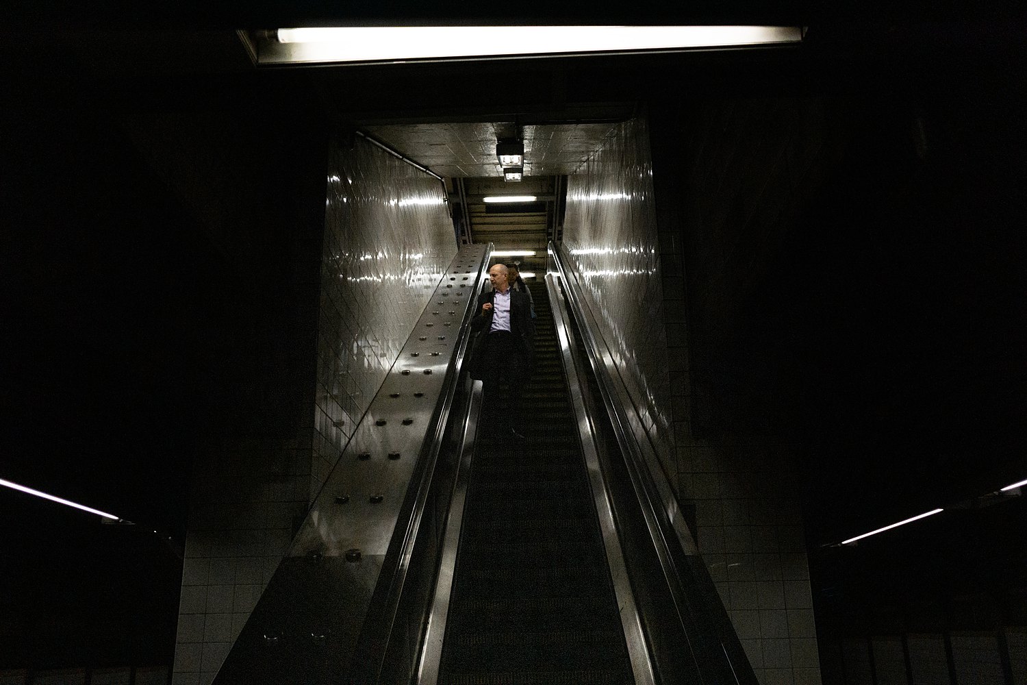 Man riding down subway escalator places to visit in New York City