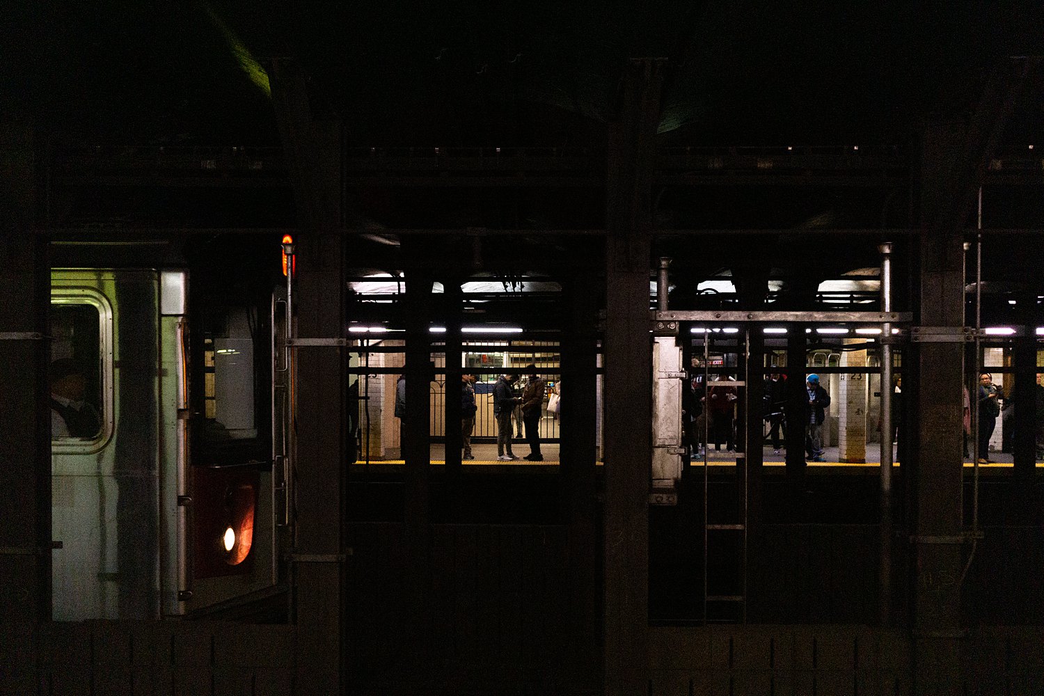 NYC subway platform with people waiting in dark places to visit in New York