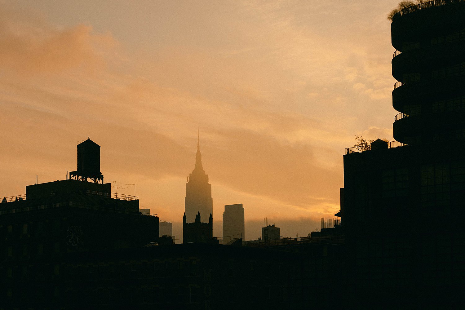 Empire State Building from distance in early morning orange sunrise and fog