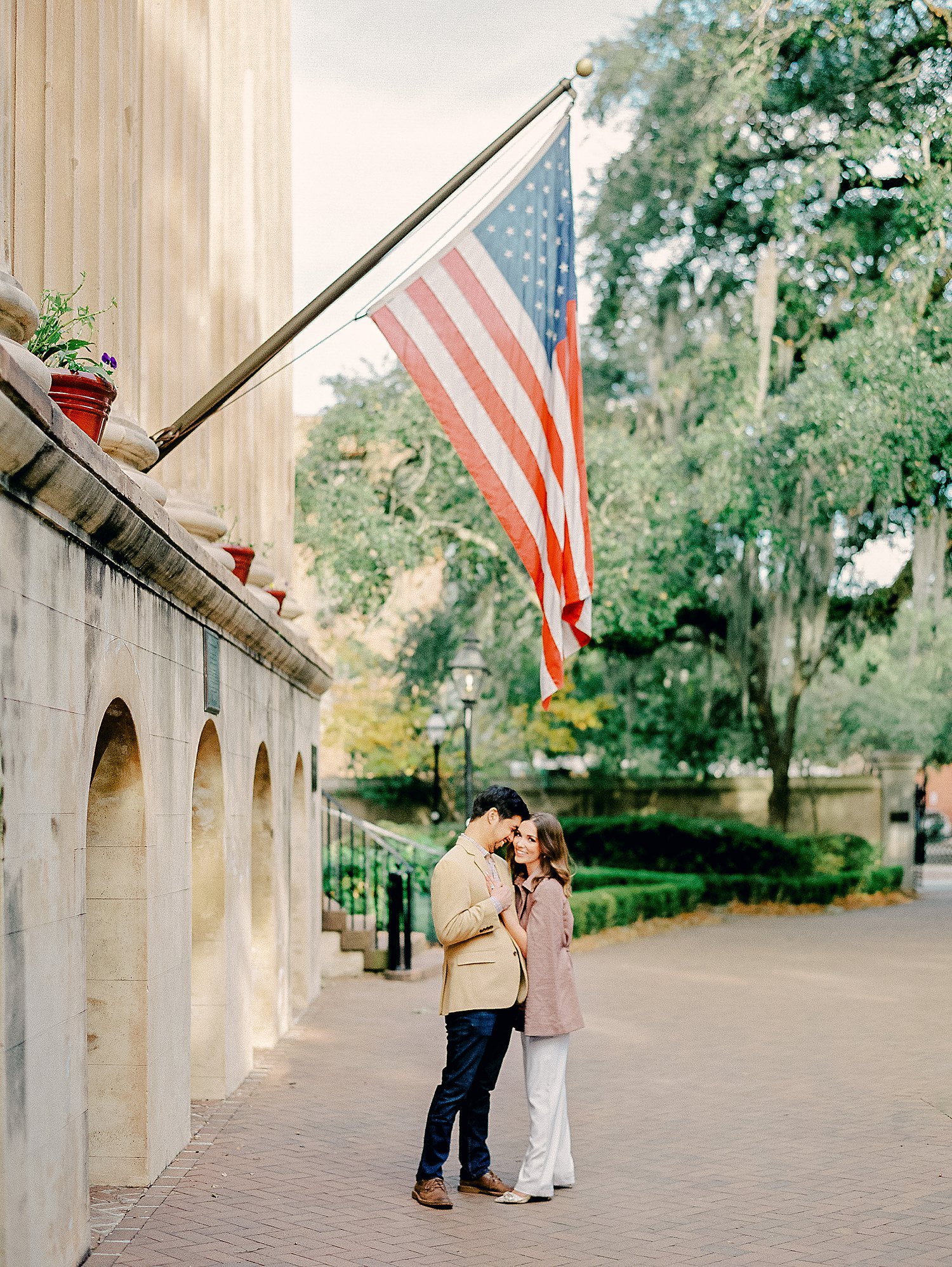 Couple Standing together laughing under American flag at College of Charleston