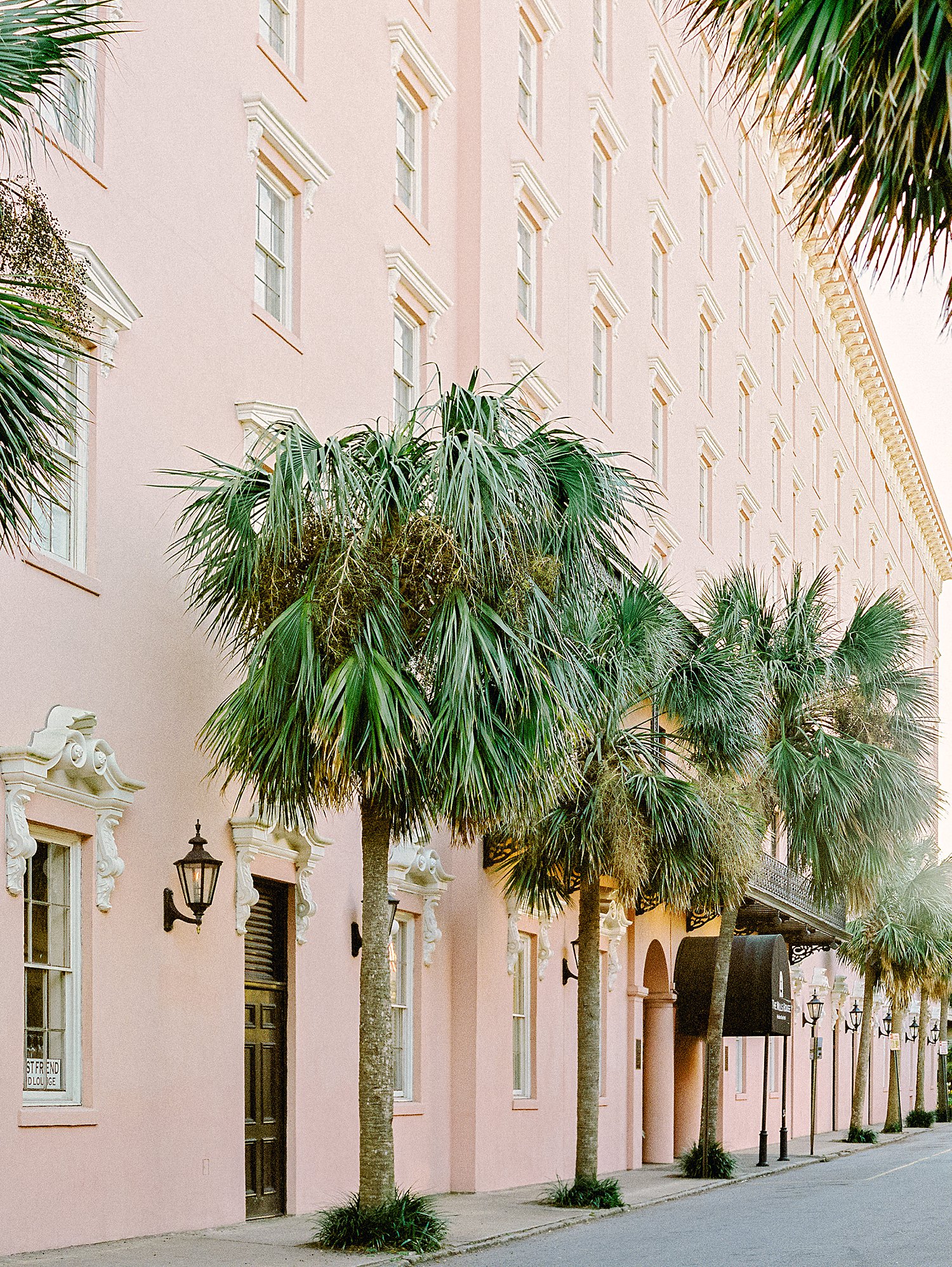 The Mill House Pink hotel facade with palm trees in Charleston