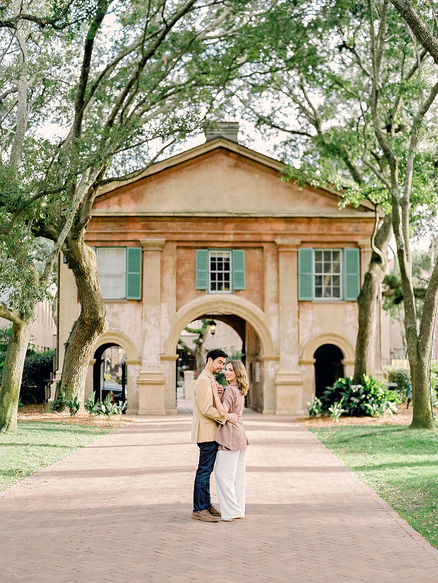 Couple embracing in front of gateway into the College of Charleston