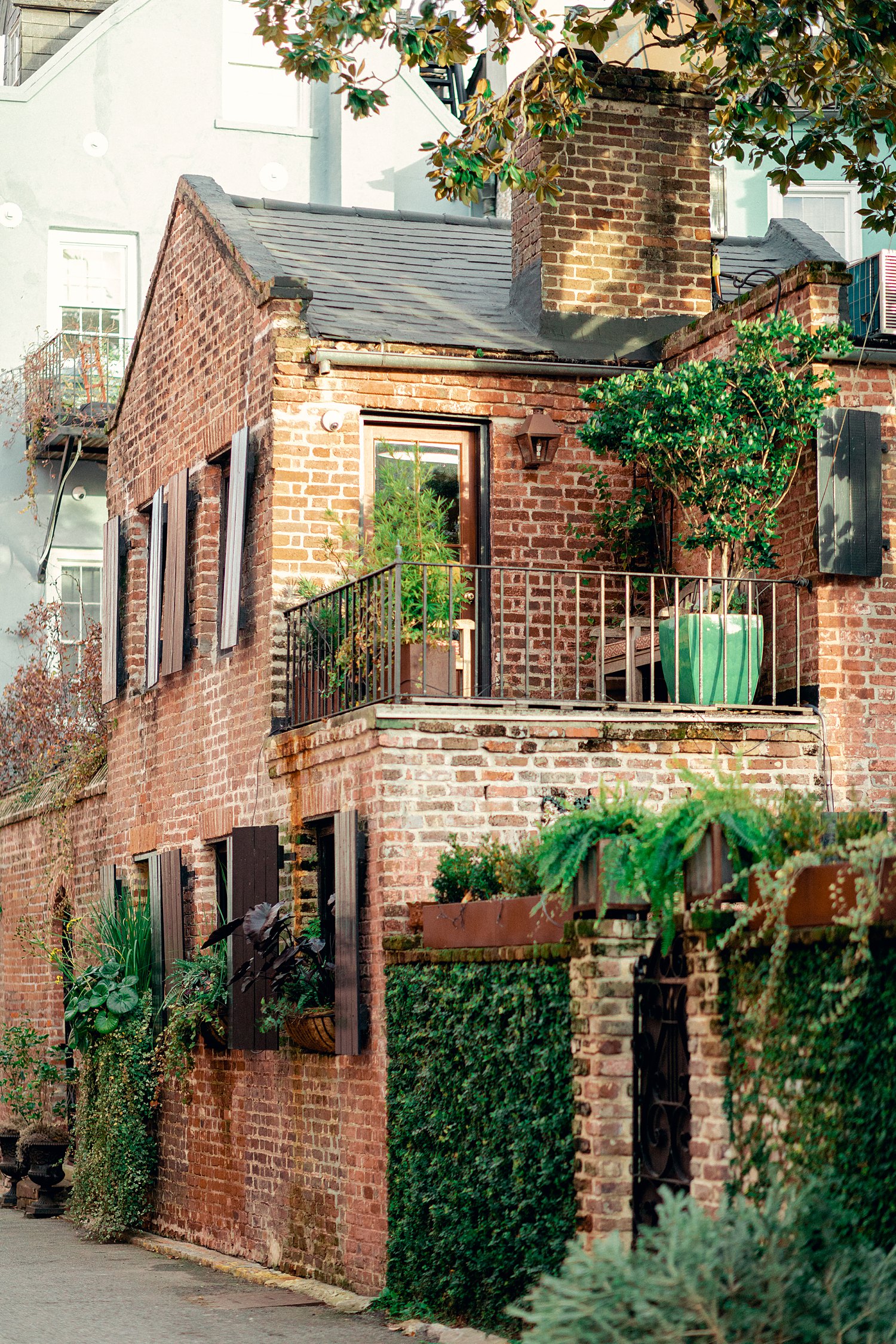 Red brick two story building surrounded by green plants in Charleston