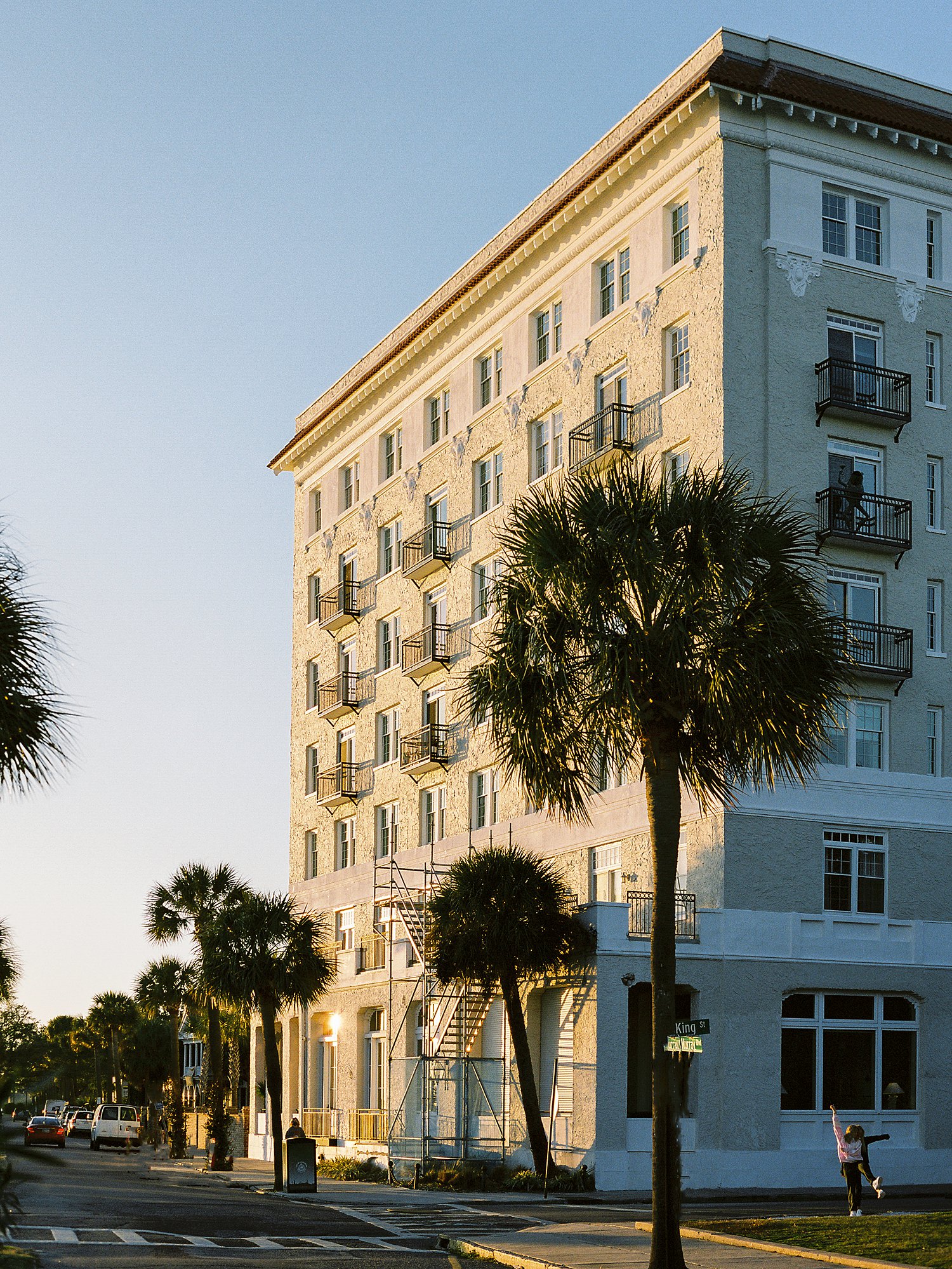 Sunset light on seven story historic building set among palm trees in Charleston