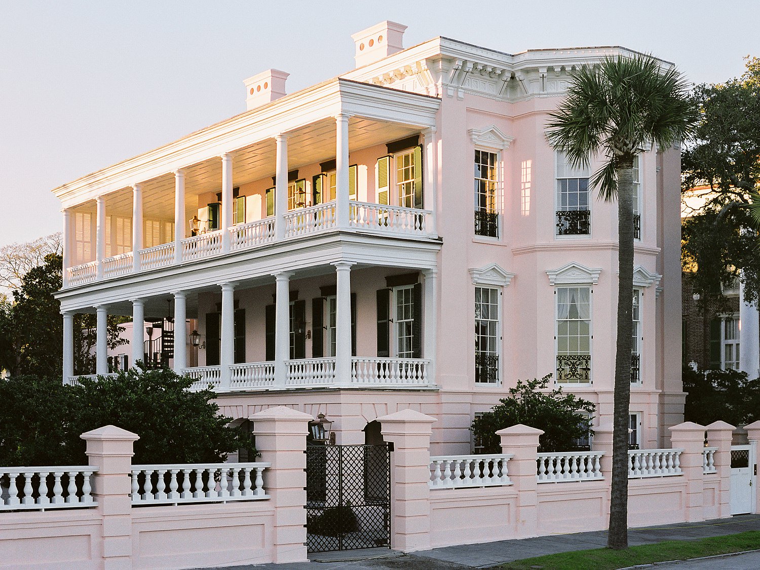 Pink three story mansion at sunset surrounded by palm trees in Charleston South Carolina