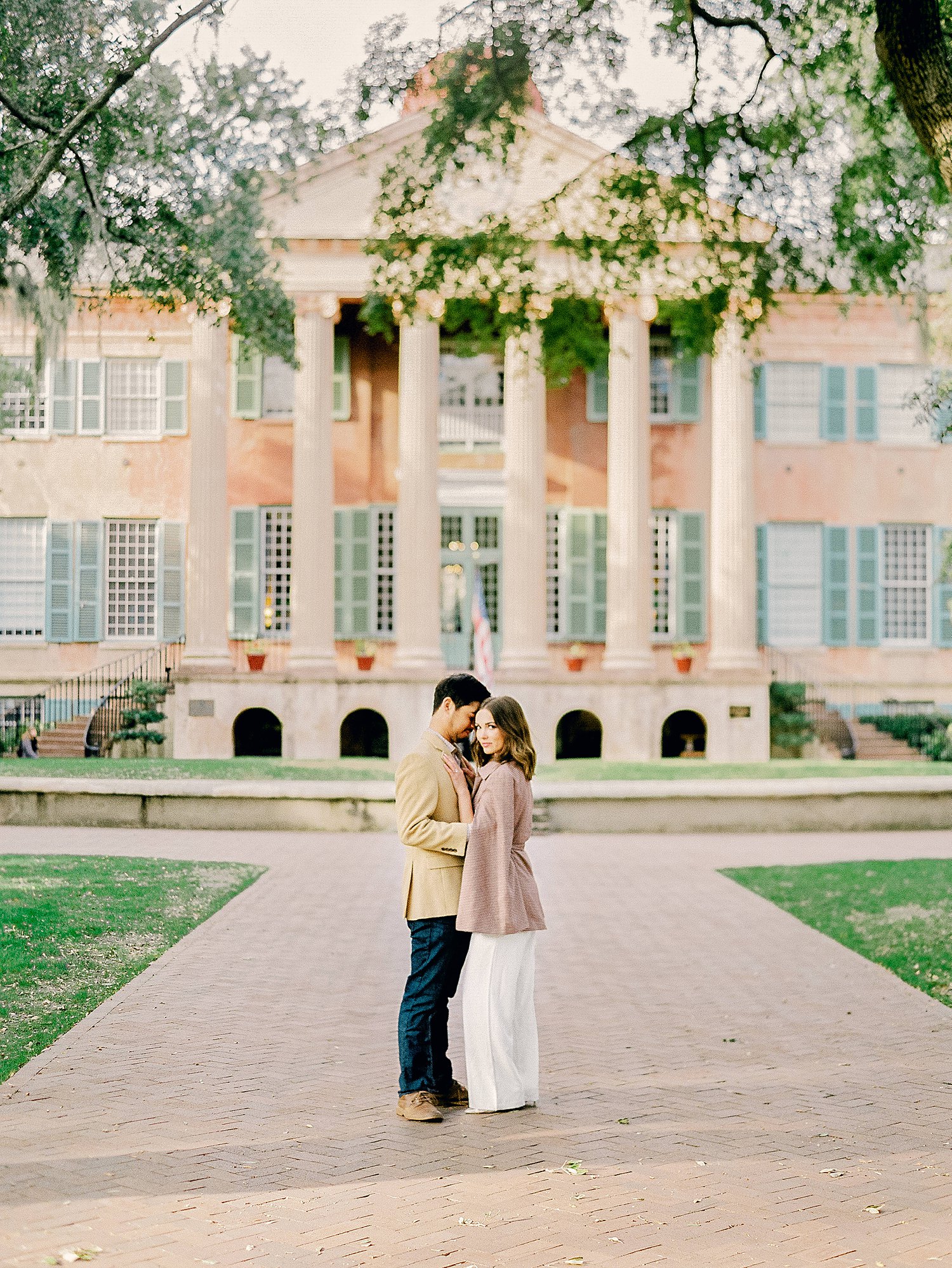 Couple embracing in front of columned building at the College of Charleston