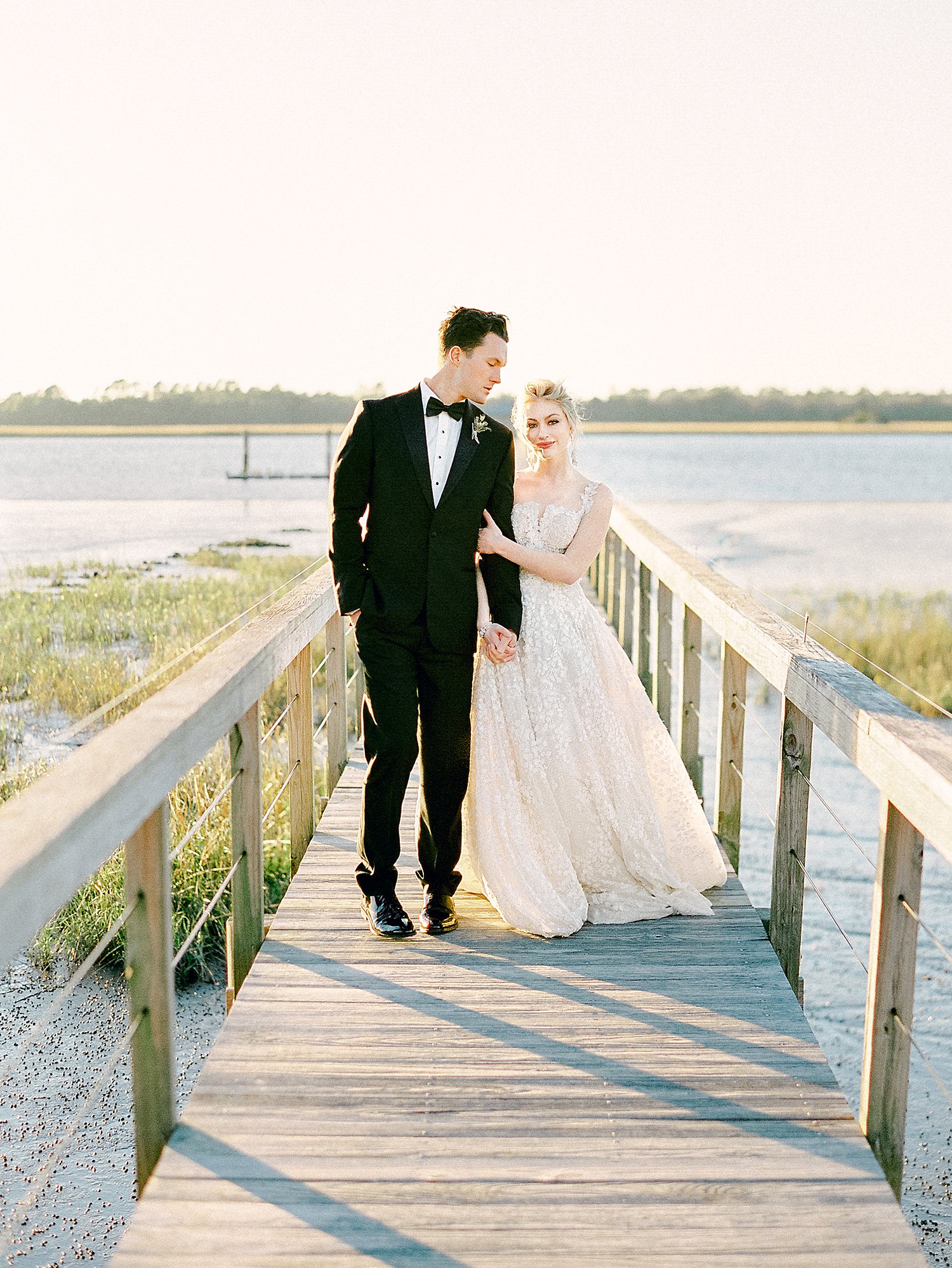 Bride and groom walking on wooden dock on river at Lowndes Grove Charleston Wedding