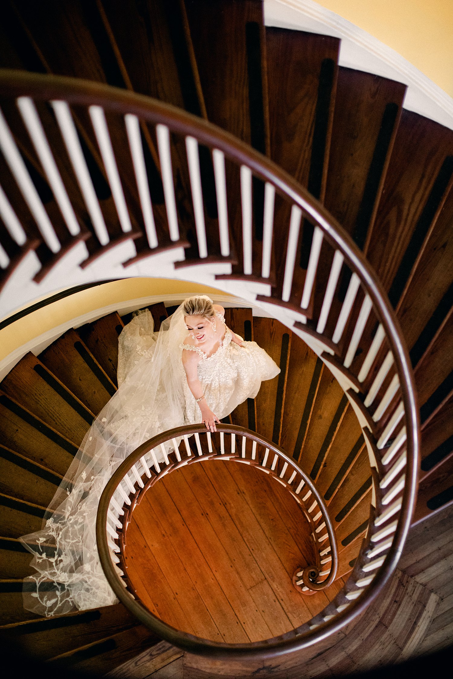bride walking down spiral staircase in white dress at Lowndes Grove Charleston Wedding