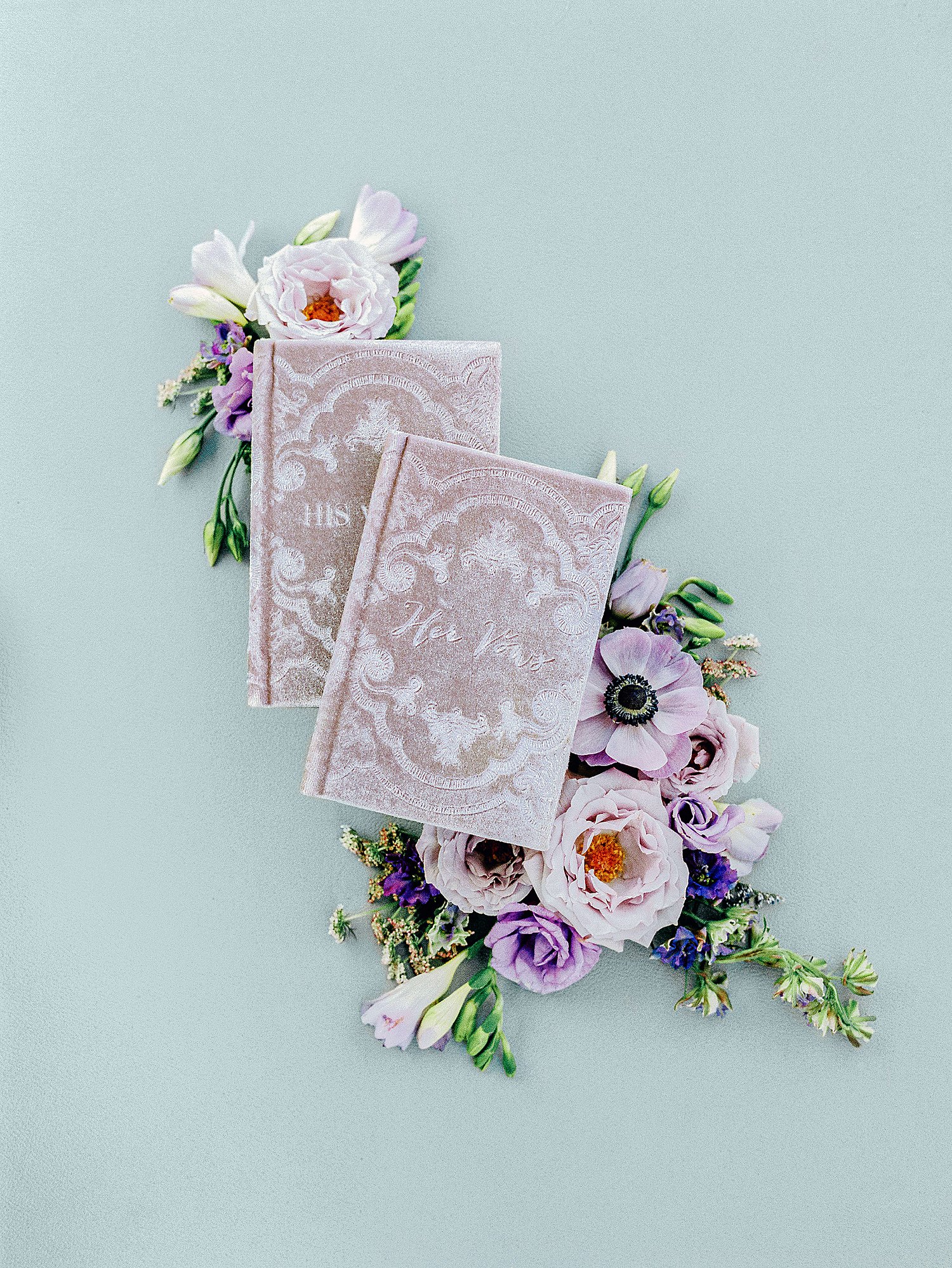 purple flowers and vow books on green background
