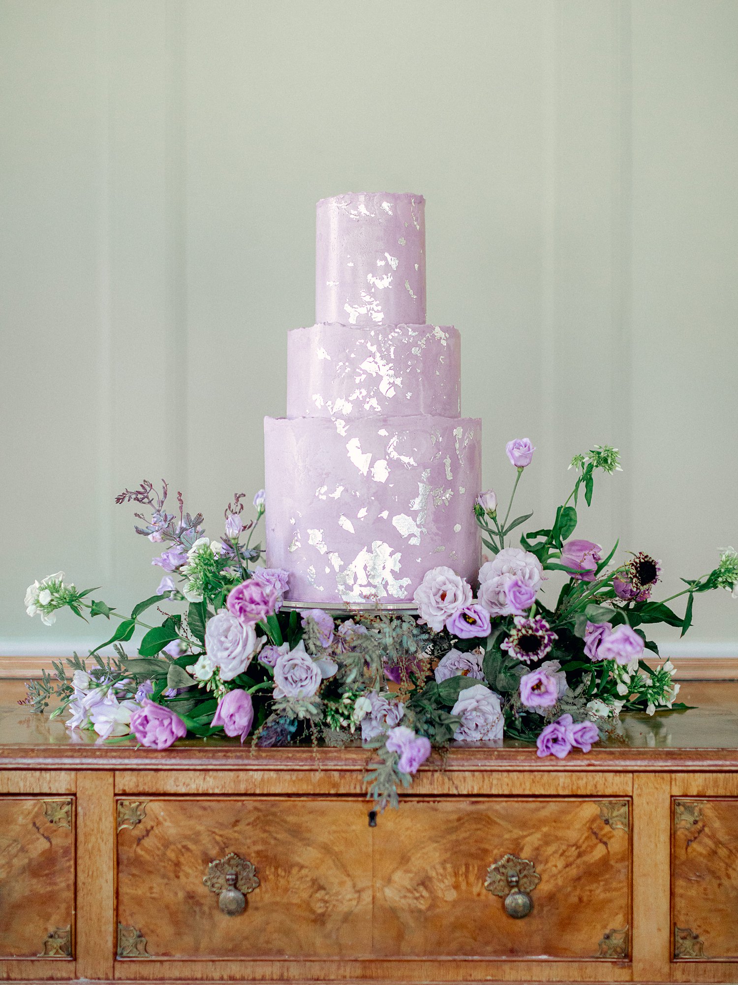 purple three tiered cake surrounded by violet florals