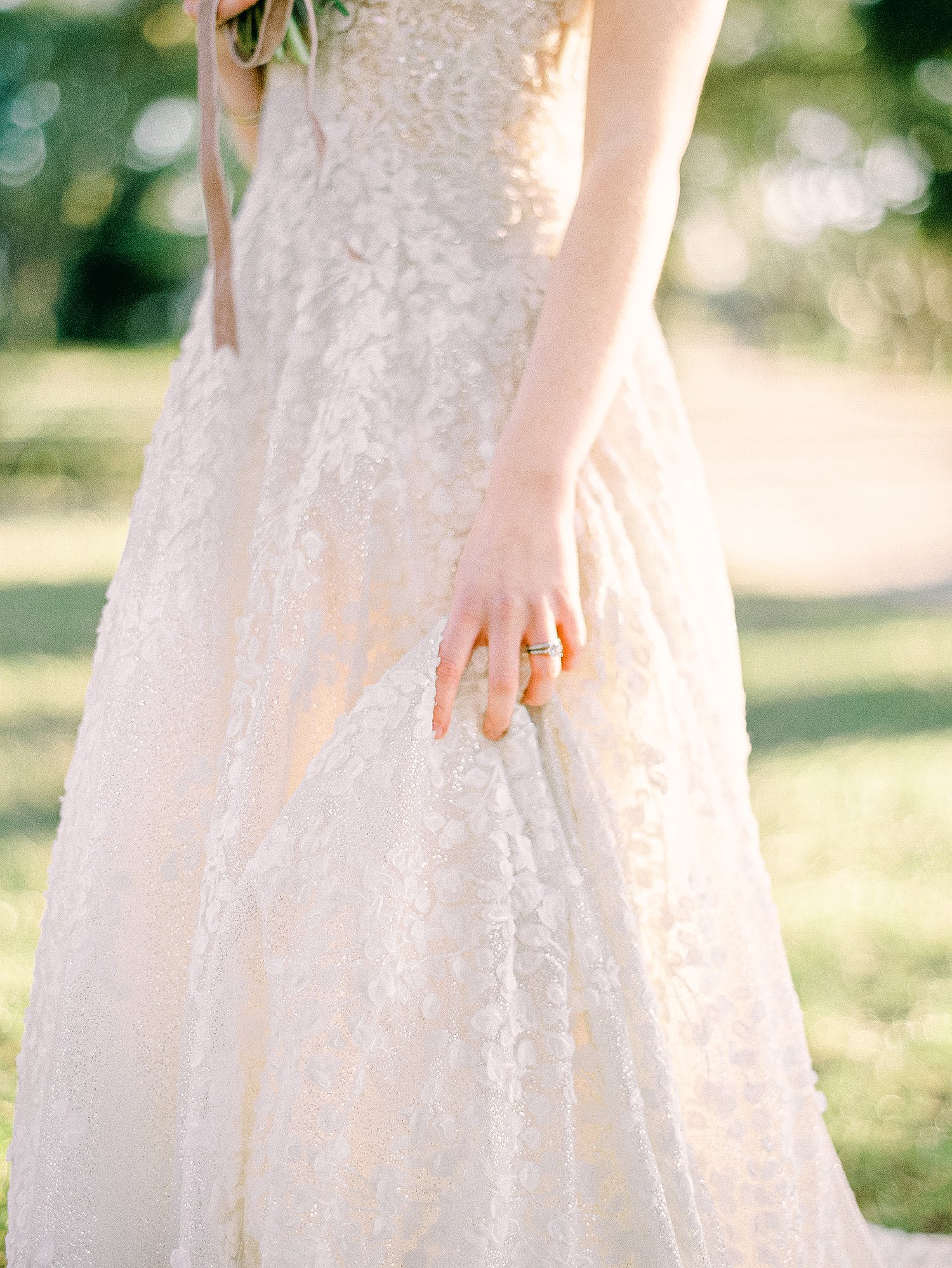 Bride's hand on white wedding dress skirt outdoors