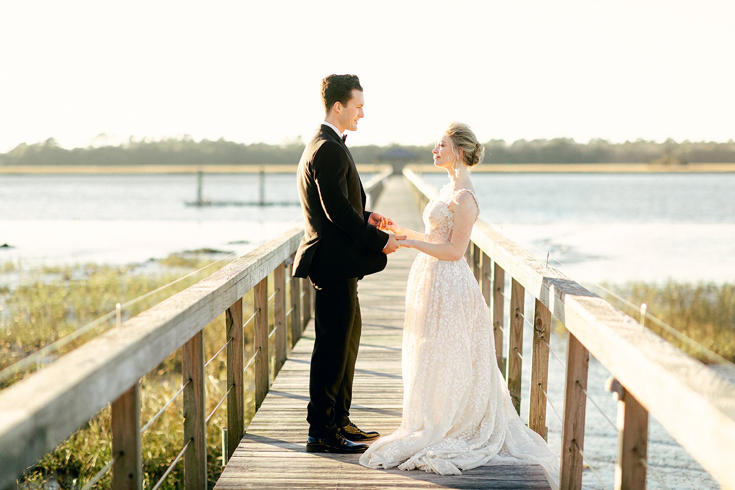 Bride and groom holding hands on wooden dock on river at Charleston Wedding