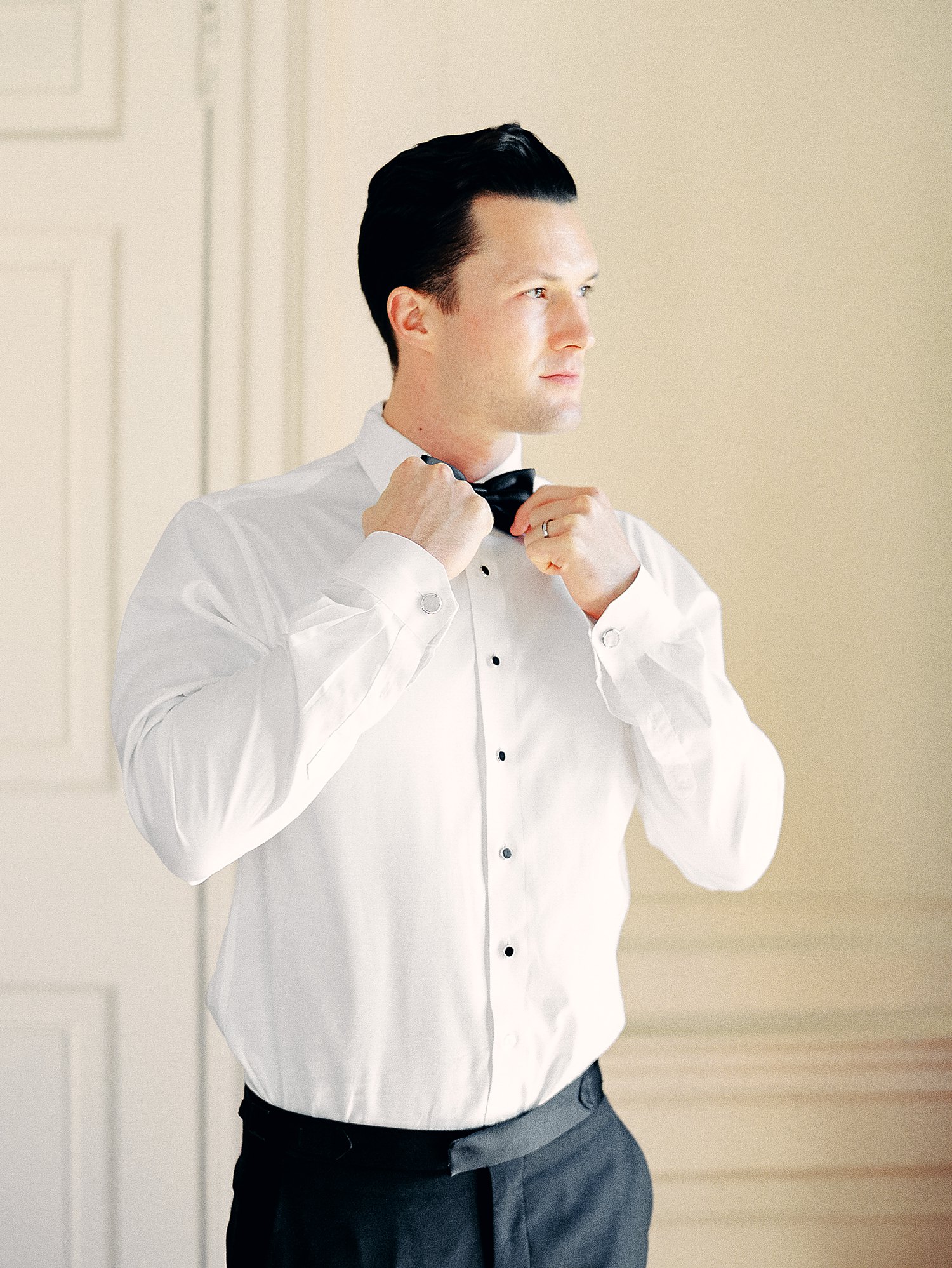 man in white shirt putting on black bowtie