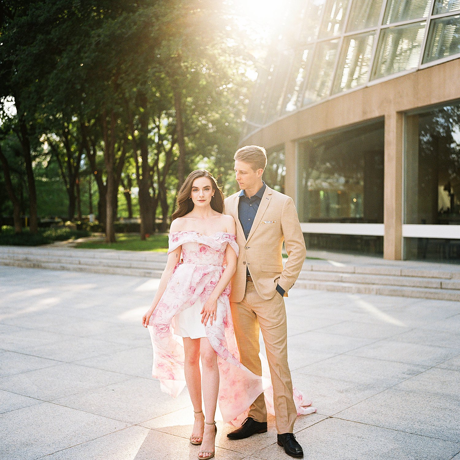 woman in Pink floral gown standing by man in tan suite and blue shirt dallas engagement