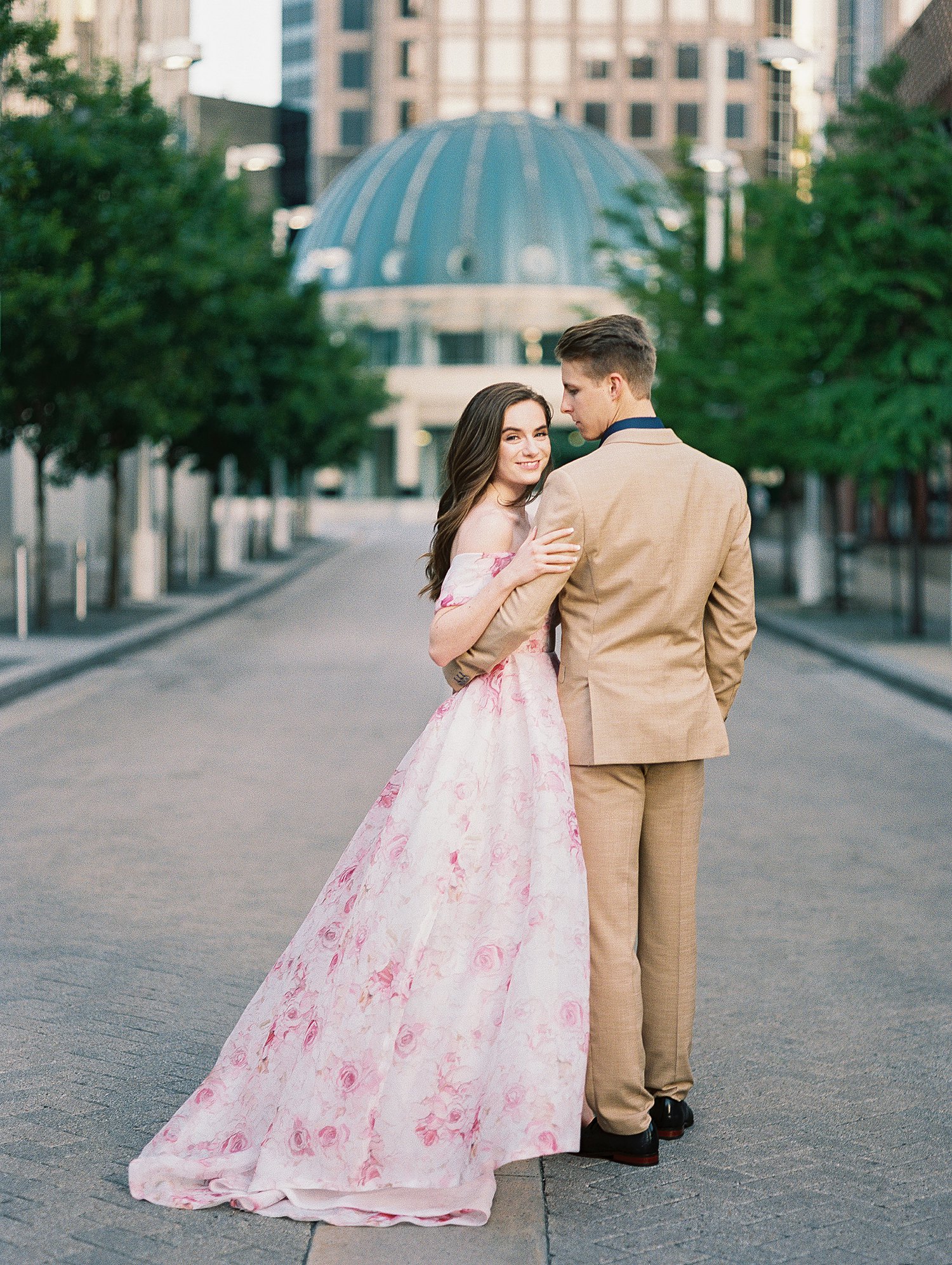 woman in Pink floral gown with man in tan suite downtown Dallas engagements on street