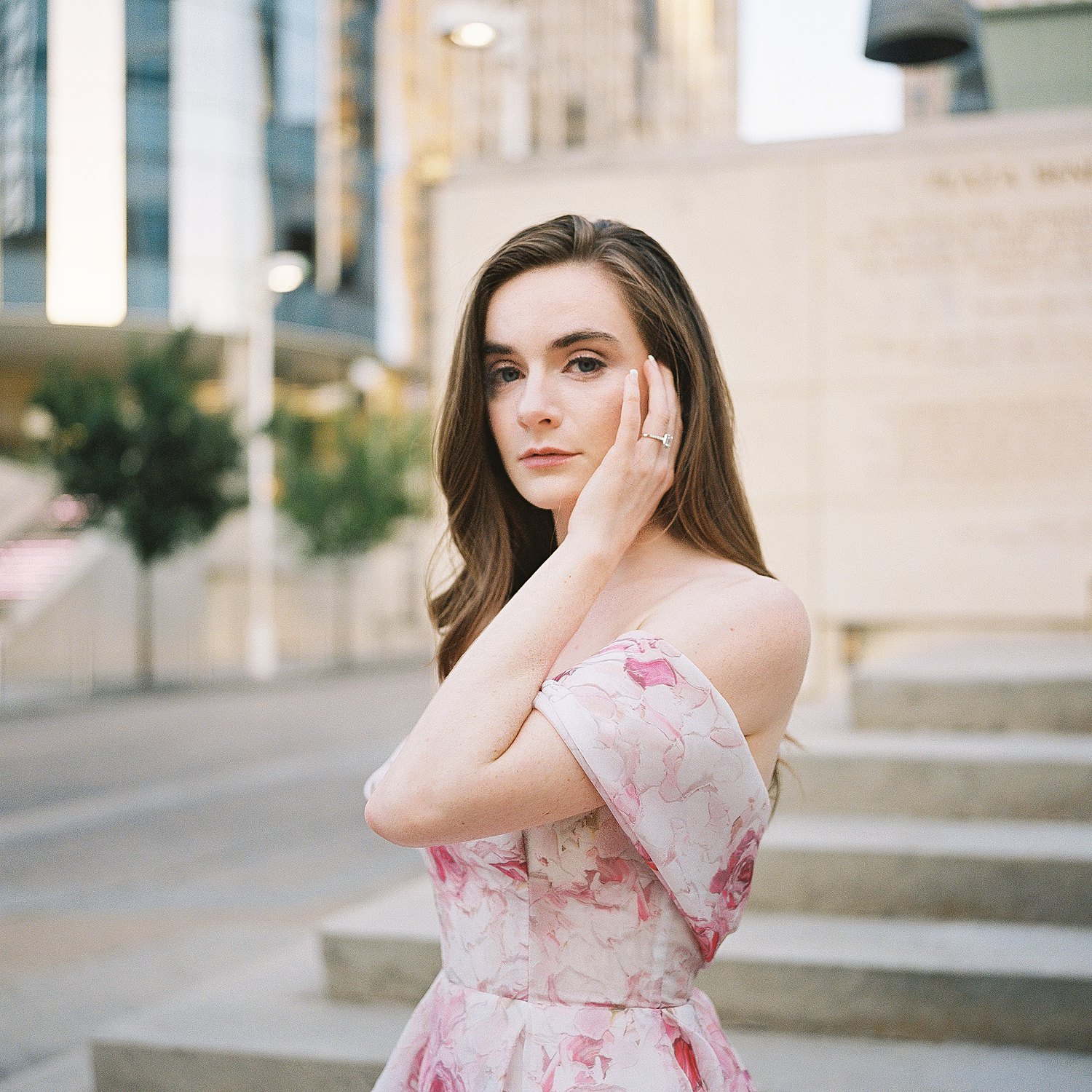 woman in Pink floral gown portrait in front urban backdrop