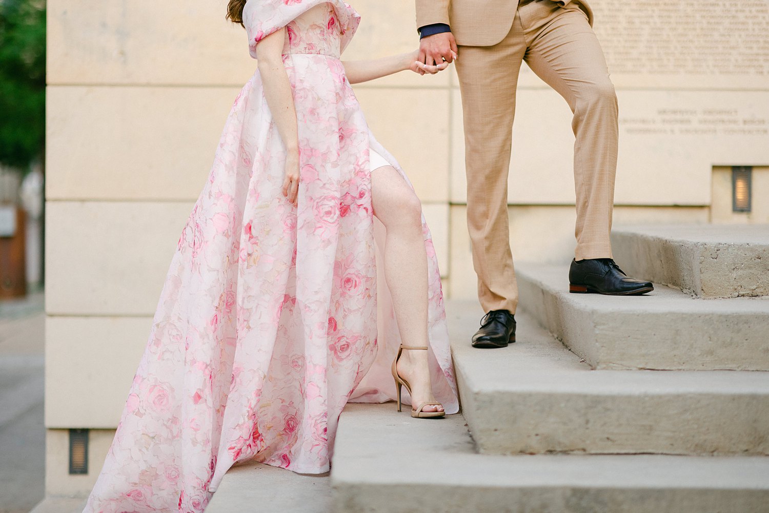 woman in Pink floral gown walking up stairs with man in tan suit
