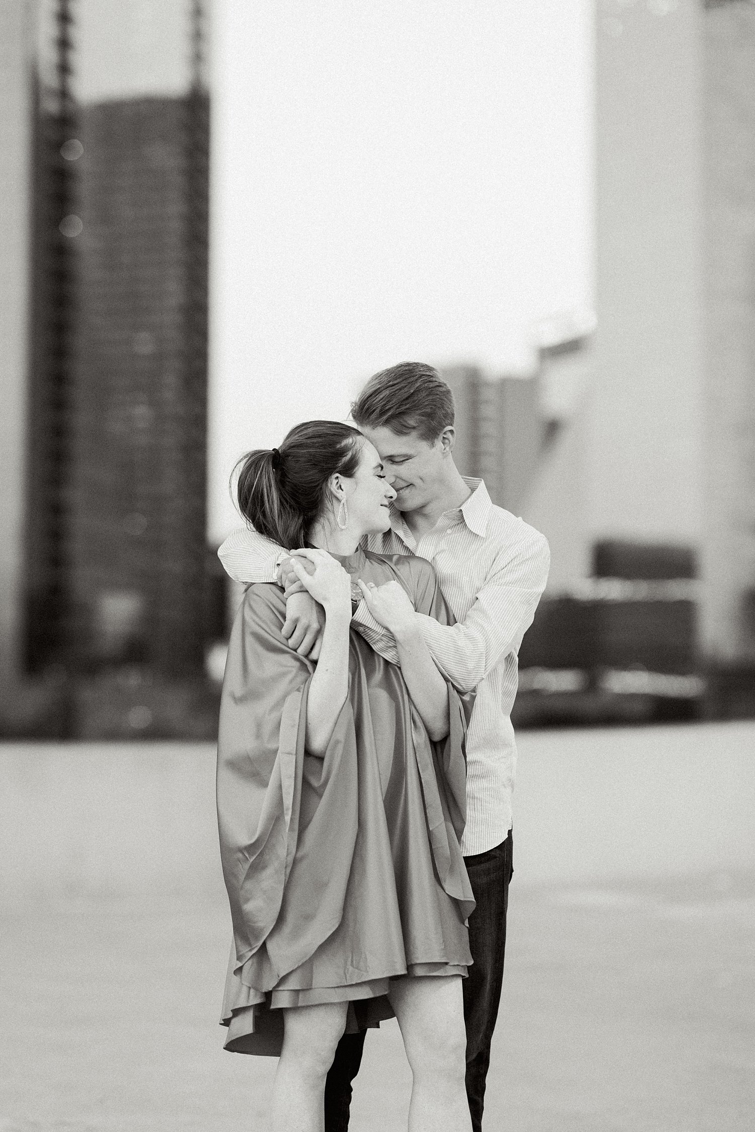 woman in dress and pony tail hugging man downtown Dallas engagement session