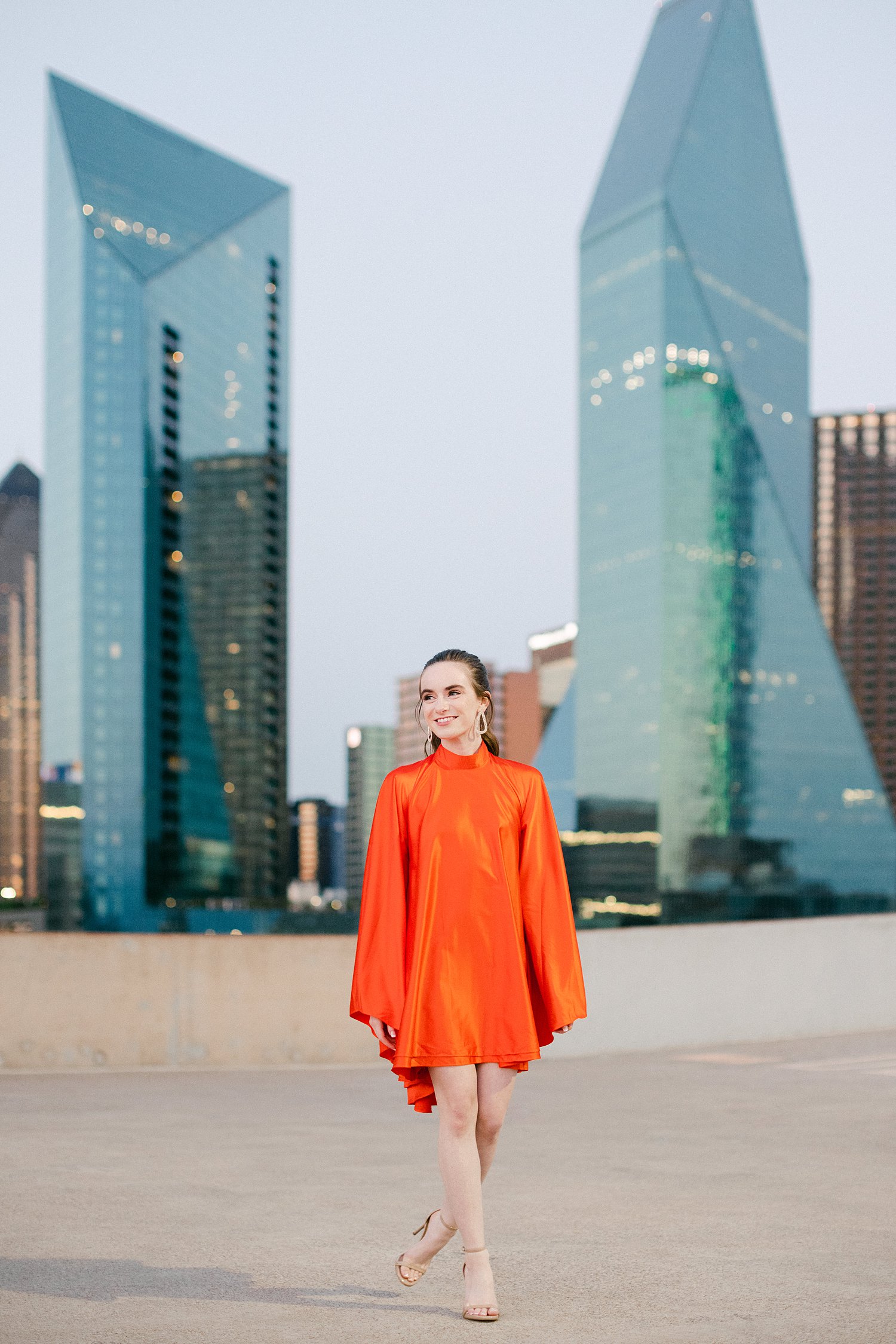 woman in orange dress and pony tail on downtown Dallas rooftop