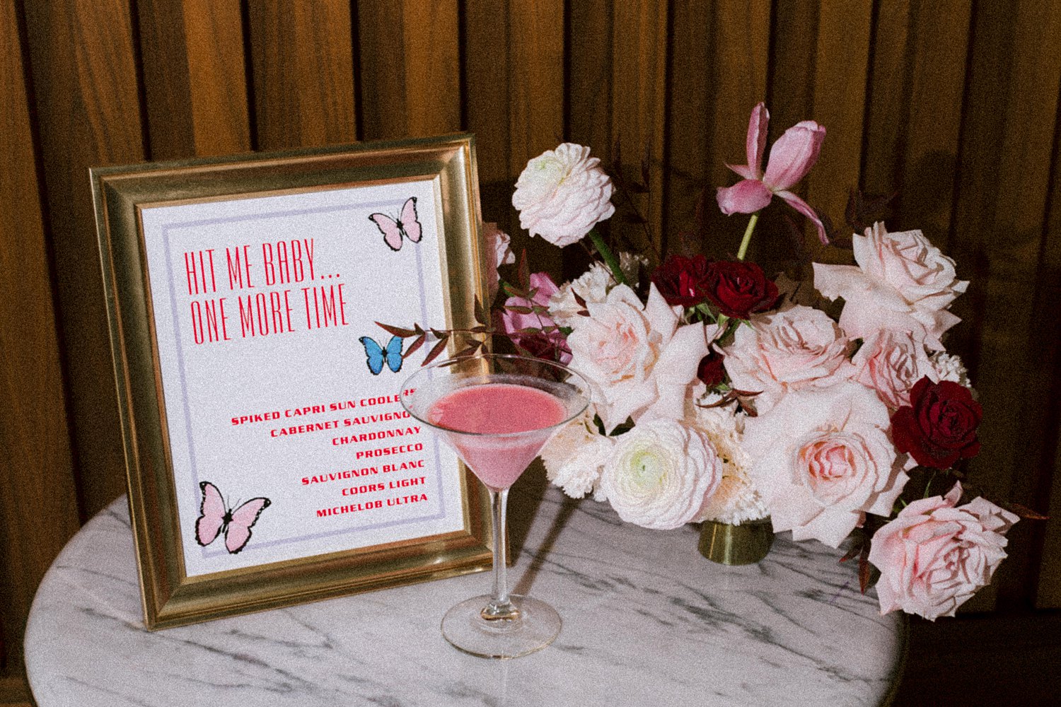 pink, purple, and blue wedding cocktail menu sitting with florals and martini