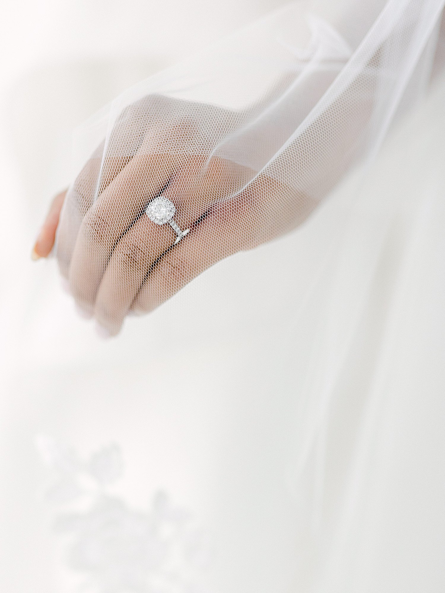 hand with diamond engagement ring under veil