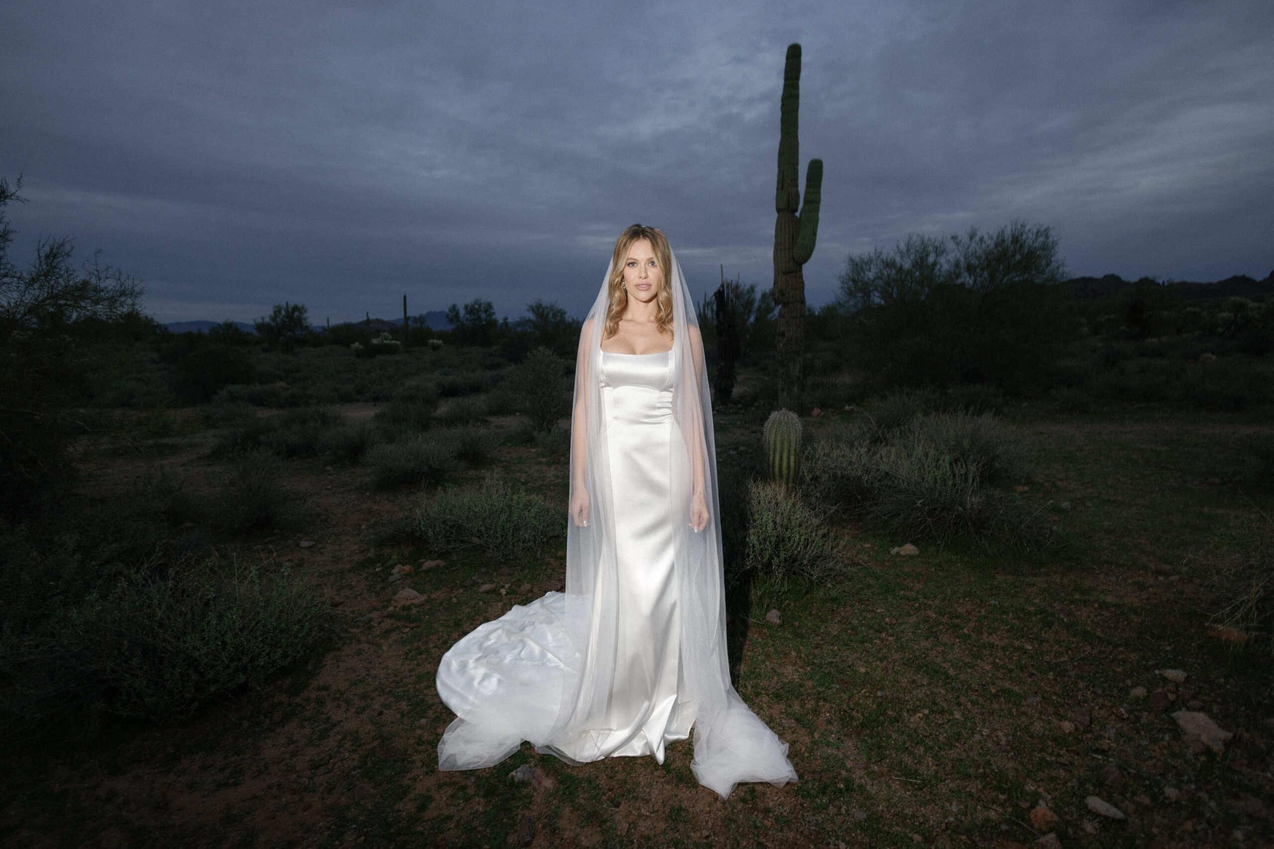 A desert bride standing in front of cactus wear under wedding dress